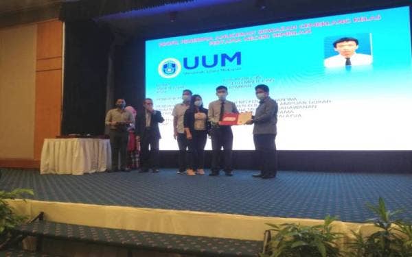 Mohamad Rafie (kanan) ketika menyampaikan penghargaan kepada siswazah terlibat pada Selasa.