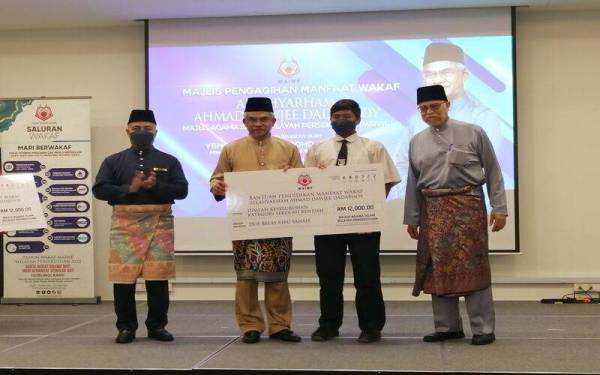 Mohd Daud (dua dari kiri) menyampaikan Wakaf Allahyarham ADD MAIWP kepada wakil kategori sekolah rendah.