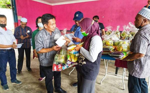 Yusuf (depan kiri) menyampaikan sumbangan kepada mangsa banjir di Dewan Terbuka Kampung Padang Empang, Baling pada Rabu.