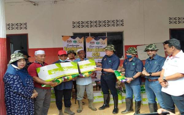 Mohd Salim (empat dari kanan) menyampaikan sumbangan Yayasan RISDA berupa kotak makanan kepada mangsa banjir dan kepala air di Kampung Masjid Iboi.