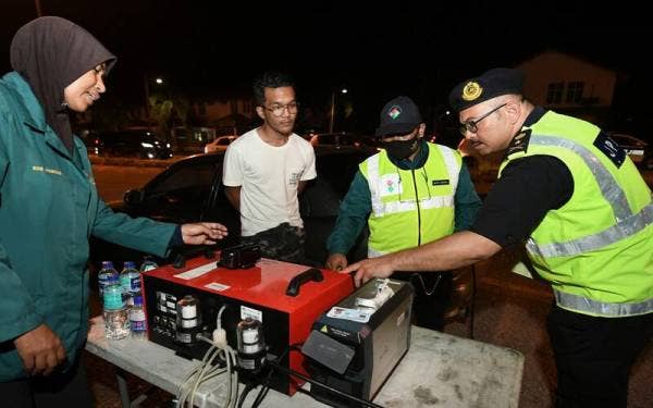 Mohd Misuari (kanan) bersama petugas JAS melakukan pemeriksaan ketumpatan asap pada Ops Khas Motosikal sempena Aidiladha di Jalan Pasir Hor-Kubang Kerian. - Foto Bernama