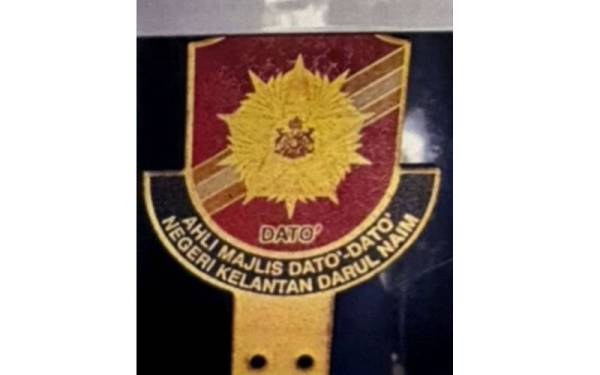 Wanita berkenaan mempamerkan lambang dan lencana Ahli Majlis Dato'-Dato' Negeri Kelantan pada dua buah kereta mewah dipercayai miliknya. - Foto Polis Kelantan