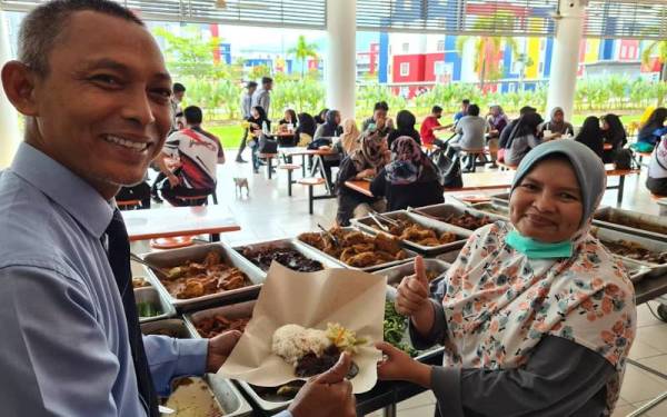 Norkhalid (kiri) bersama pemilik kafe, Ade Idriani menunjukkan menu Keluarga Malaysia yang disediakan UPSI. - Foto ihsan UPSI