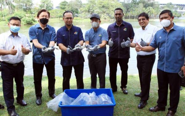 Rizalman (tiga dari kiri) bersama Ismail (empat dari kiri) dan De Leong (dua dari kiri) menunjukkan ikan yang dilepaskan ke dalam tasik pada pelancaran SWCorp Karnival BersamaMu yang diadakan di Taman Tasik Permaisuri.