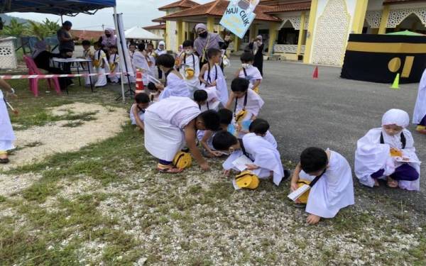 Murid-murid mengutip batu untuk melontar pada
Program Haji Cilik 2022.
