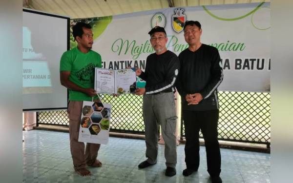 Exco Pertanian dan Industri Makanan Negeri Sembilan Datuk Bakri Sawir (tengah) menyampaikan sijil pelantikan kepada jurupandu Gua Batu Maloi. Hadir sama Pengarah JPNS Saleh Awaludin (kanan)