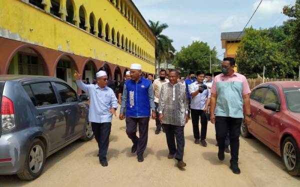 Idris (dua dari kiri) meninjau kerosakan akibat banjir dan kepala air di SMA Arab Yayasan Khairiah Kupang, Baling pada Ahad.