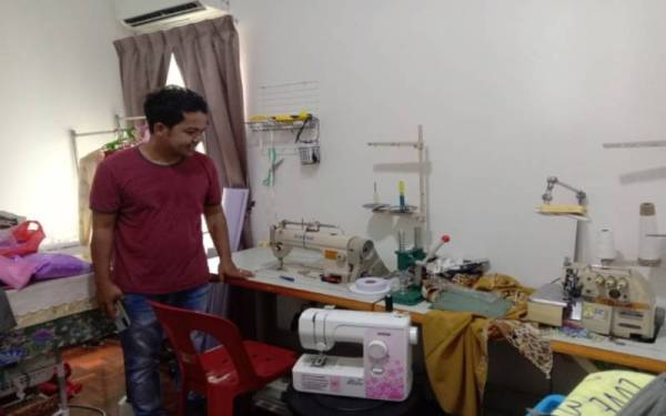 Mohd Razali menunjukkan mesin jahit yang dibelinya.
