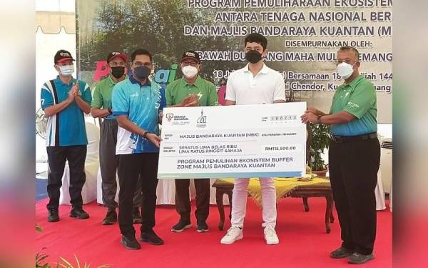 Baderul Sham (kanan) menyerahkan replika cek peruntukan Program Pemuliharaan Ekosistem Zon Penampan kepada Hamdan sambil disaksikan Tengku Hassanal Ibrahim Alam Shah dan Wan Rosdy di Pantai Chendor, Kuantan pada Isnin.