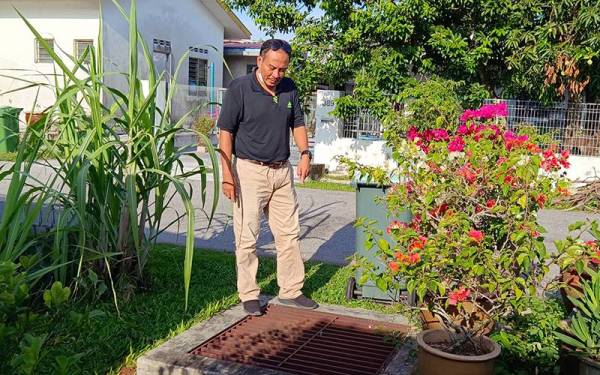 Abdul Salim menunjukkan longkang yang menjadi punca banjir kilat melibatkan dua rumah penduduk kampung di Jalan Kemuning, Manjoi.