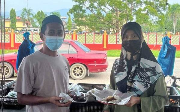 Zuraida (kanan) bersama suaminya menunjukkan nasi lemak berharga RM1 sebungkus yang dijual di kedainya.