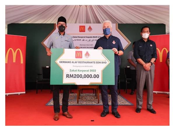 Mohamad Rizam (kanan) menyampaikan sumbangan daging korban daripada McDonald’s kepada seorang penerima.