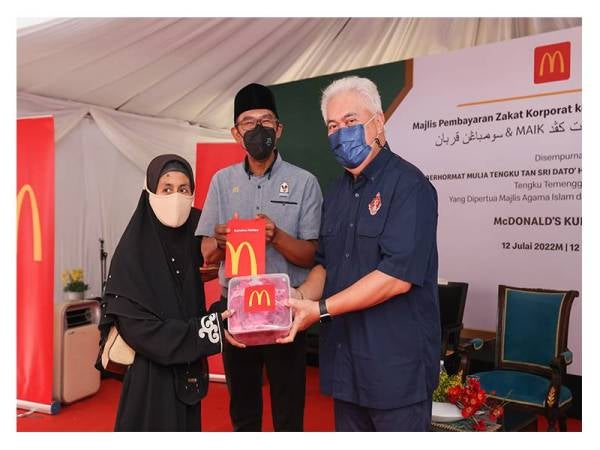 Mohamad Rizam (kanan) menyampaikan sumbangan daging korban daripada McDonald’s kepada seorang penerima.
