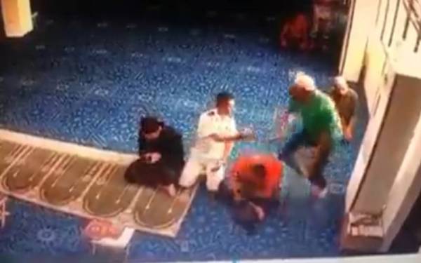 Tangkap layar video menunjukkan lelaki (berbaju hijau) memukul kepala seorang jemaah selepas selesai menunaikan solat Asar di Lumut. Foto: Ihsan pembaca