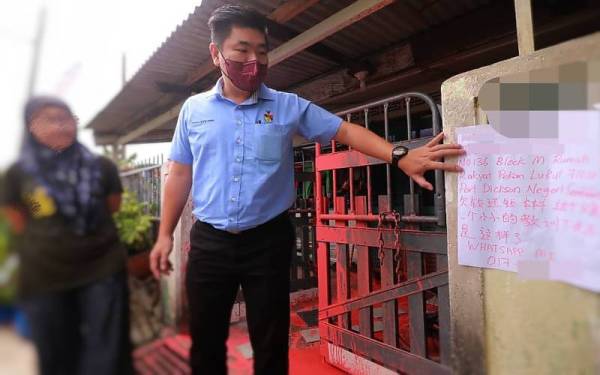 Choo Ken Hwa (kanan) melihat notis yang dipercayai ditampal oleh ah long yang tersalah rumah.