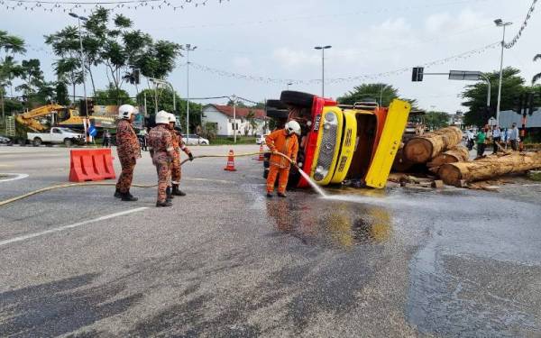 Anggota bomba membersihkan kesan tumpahan minyak di atas jalan. - Foto ihsan Polis Hulu Terengganu
