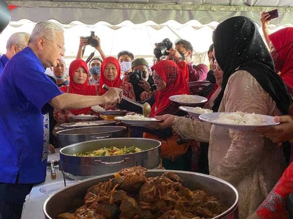 Ismail Sabri (kiri) melayan orang ramai mendapatkan makanan semasa program ‘bekwoh’ sempena Jelajah Aspirasi Keluarga Malaysia di YKK Peringat, Kota Bharu pada Sabtu.