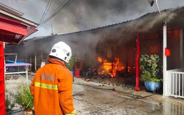Anggota bomba menjalankan operasi memadam kebakaran melibatkan lima rumah penduduk di Kuala Kurau. - Foto ihsan Bomba Perak