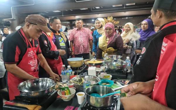 Akramuddin (tiga dari kiri) menemani Salhah (lima dari kiri) melihat peserta membuat persiapan memasak asam pedas di Muzium Istana Melayu Melaka, Banda Hilir pada Sabtu.