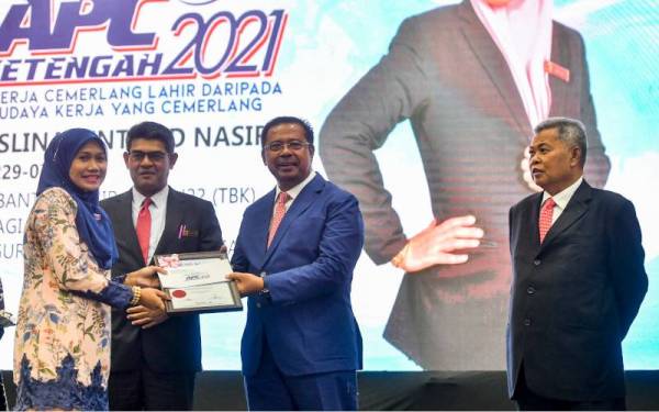 Abdul Rahman (tengah) menyampaikan Anugerah Perkhidmatan Cemerlang kepada Roslina Nasir (kiri) pada majlis berkenaan peringkat Ketengah di Bandar Al Muktafi Billah Shah, pada Ahad. Memerhatikan ialah Ahmad (kanan). - Foto Bernama