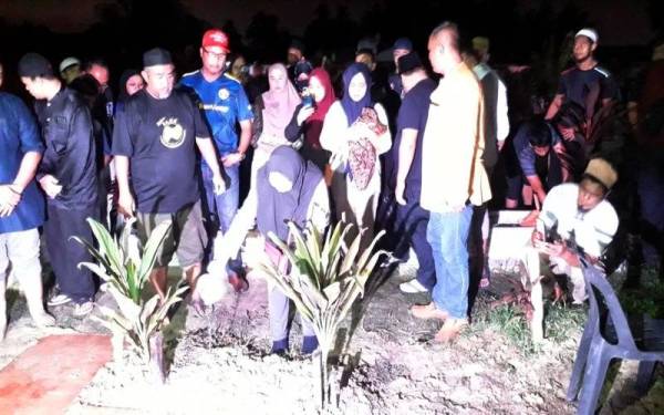 Azmawati menyiram pusara Allahyarham Muhammad Iman Aqmar Dzulkarnain yang dikebumikan di Tanah Perkuburan Islam Kampung Pasir Putih, Pasir Gudang, awal pagi Selasa.