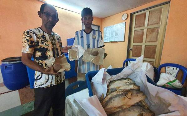 Mazlan (kiri) dan Mohd Rusli menunjukkan produk hasil laut yang diusahakan mereka bagi menambah pendapatan.