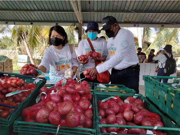 Siuew Luan (kiri) bersama Thinesh dan Hanim melihat barangan runcit yang diagihkan kepada penduduk  bagi program 'Kelantan Dekat Di Hati'.