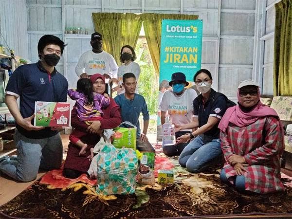 Siuew Luan (berdiri, kanan) dan pasukan sukarelawan bergambar bersama keluarga Nurul Aisyah selepas menyampaikan kereta sorong kepada kanak-kanak itu sempena 'Kelantan Dekat Di Hati'.