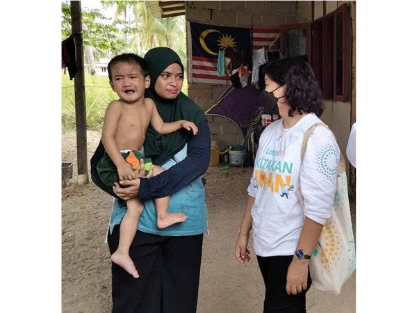 Siuew Luan (kiri) bertanya khabar ibu Iman Fayadh, Wan Nor Suriyani Wan Yahya, 33, mengenai kesihatan kanak-kanak itu ketika lawatan pada Jumaat.