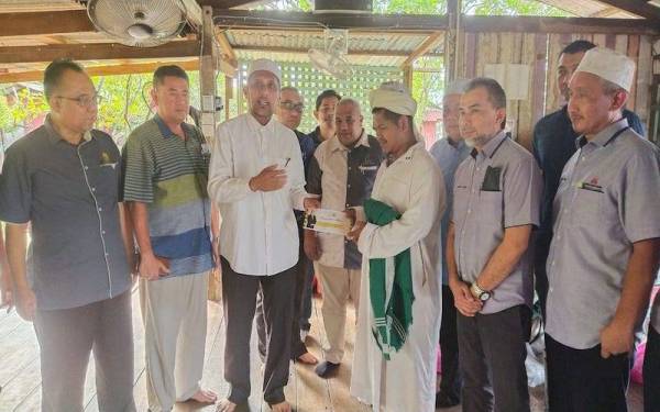 Syed Ibrahim menyerahkan sumbangan wang tunai keperluan kepada Zaidi untuk membantu meringankan beban ditanggung pihak pengurusan Madrasah Al Imaniyah, Kampung Darat Sungai Ular di sini yang terlibat dalam kebakaran Ahad lalu.