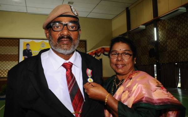 S Megalavathi (kanan) menunjukkan pingat Jasa Pahlawan Negara yang diterima suaminya, Narynen sempena Majlis Penganugerahan Pingat Jasa Pahlawan Negara Kontinjen Johor siri 2/2022 di IPK, Johor Bahru pada Rabu.