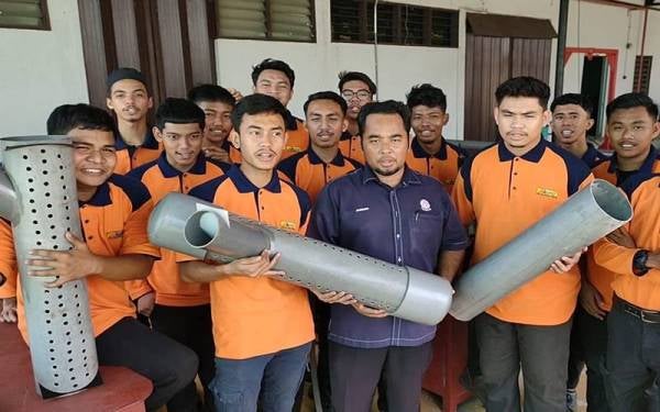 Marzuki (tengah) bersama 16 pelajar IKM Tan Sri Yahaya Ahmad yang mereka cipta perangkap tikus menggunakan paip PVC.