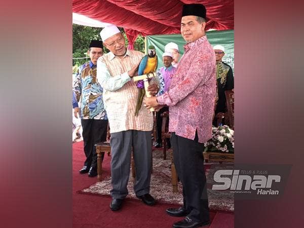 Ahmad (dua dari kiri) memegang burung kakak tua pada gimik perasmian Mini Zoo Kuala Krai pada Khamis.