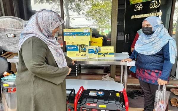 Anis Afarina (dua dari kiri) gembira menerima bantuan meja tebar roti canai pada Jumaat.
