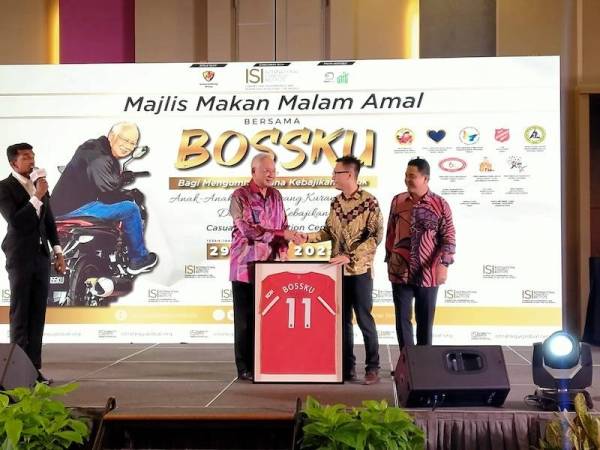 Najib (kiri) menyerahkan jersi Manchester United 'Bossku' kepada Vermillion Ng yang berjaya memenangi bidaan maksimum RM50,000 pada Majlis Makan Malam Amal Bersama Bossku di Pusat Konvensyen Casuarina pada Jumaat.