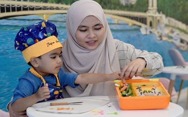 Nurul Azren (kanan) membantu Zhafran Umar semasa menghasilkan bekal hidangan sihat selepas mereka tular di laman sosial kerana suara latar Umar ketika ditemui di Seksyen 7. - Foto Bernama