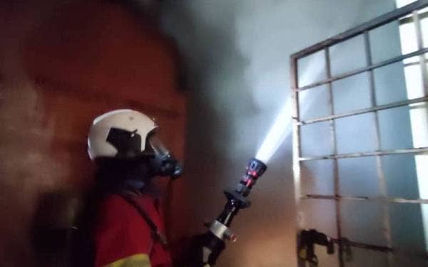 Anggota bomba memadamkan kebakaran melibatkan asrama pekerja di sebuah rumah kedai di Jalan Batu Unjur 1, Bandar Bukit Tinggi pada Ahad.