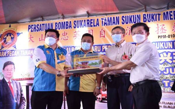 Kon Yeow (kanan) menerima cenderamata selepas menyampaikan sumbangan RM50,000 untuk membina balai baharu Bomba Sukarela Taman Sukun pada Ahad.