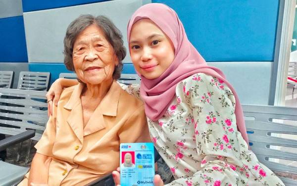 Rohana bersama ibu angkatnya menunjukkan kad pelajar selepas mendaftarkan diri sebagai pelajar di UTeM, Durian Tunggal di sini pada Isnin.