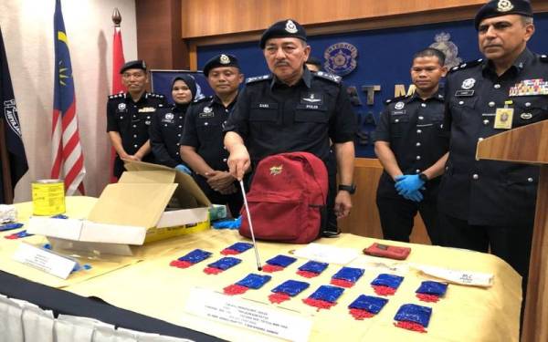 Muhamad Zaki (tiga dari kanan) menunjukkan pil kuda yang dirampas di sebuah rumah di di Felda Kemahang 3 di Tanah Merah.