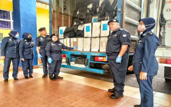 Norlela (tiga, kanan) menunjukkan rokok seludup yang berjaya dirampas pada sidang akhbar di pejabat JKDM Melaka di Ayer Keroh pada Selasa.