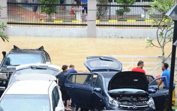 Beberapa pemilik kenderaan di Jalan Ayer Molek melihat kenderaan mereka yang dinaiki air berikutan banjir kilat beberapa jam di bandaraya Johor Bahru. Foto Bernama.