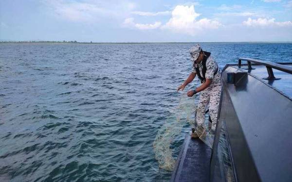 Anggota Maritim Malaysia mengangkat bubu naga yang dipasang pihak tidak bertanggungjawab.