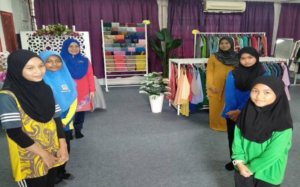 Umaimah (tiga kiri) menguruskan Butik Qaseh SKSP bersama ahli BKGS dan dibantu murid SKSP.