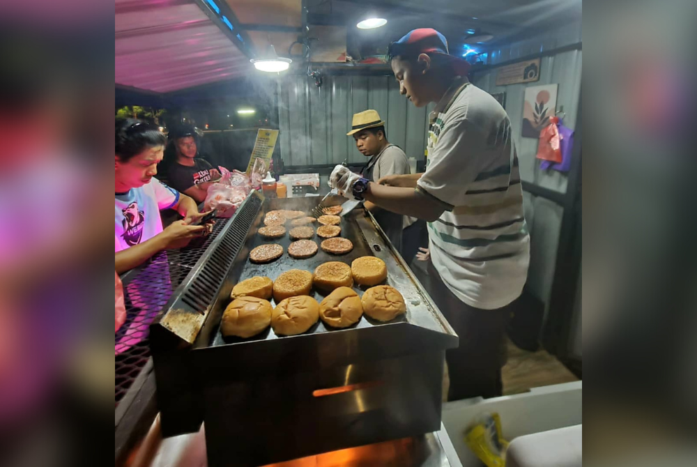Pekerja sedang menyediakan burger yang dipesan oleh pelanggan.