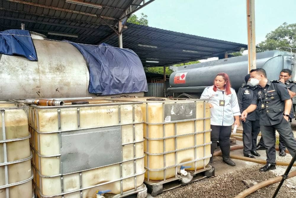 Norena (kiri) menunjukkan tangki yang digunakan untuk menyimpan minyak diesel di sebuah premis di krubong, pada Jumaat.