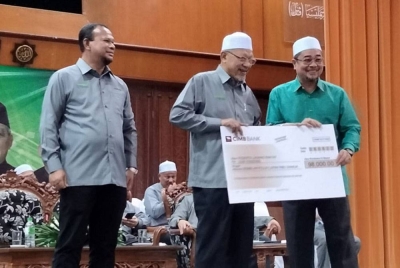 Mohd Zain (kiri) mengiringi Ahmad menyampaikan replika cek dividen kepada wakil Dewan Undangan Negeri ketika Himpunan Perdana Peserta Ladang Rakyat Negeri Kelantan dan Pembahagian Dividen Ladang Rakyat Peringkat Ke-56 pada Sabtu