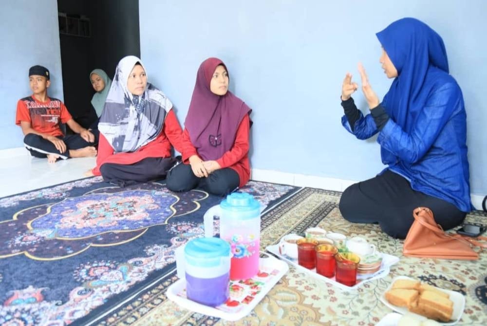 Nor Haslynda (kanan) berkomunikasi dengan Umi Aqilah menggunakan bahasa isyarat memandangkan pelajar itu menghadapi masalah pendengaran dan pertuturan. - Foto PTSS