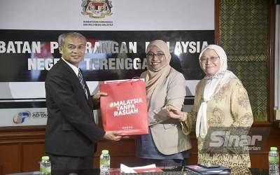 Nurhayati (tengah) menyampaikan cenderahati kepada Sait selepas kunjungan pasukan Rasuah Busters ke Jabatan Penerangan Negeri Terengganu pada Ahad.