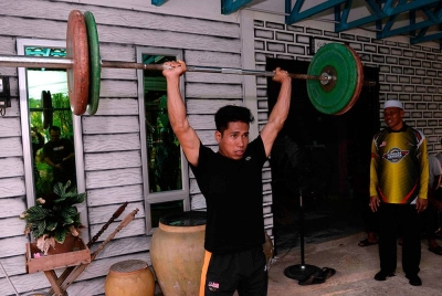 Muhmammad Aznil menunjukkan cara mengangkat berat di Kampung Baru Bukit Pinang pada Ahad. Foto Bernama